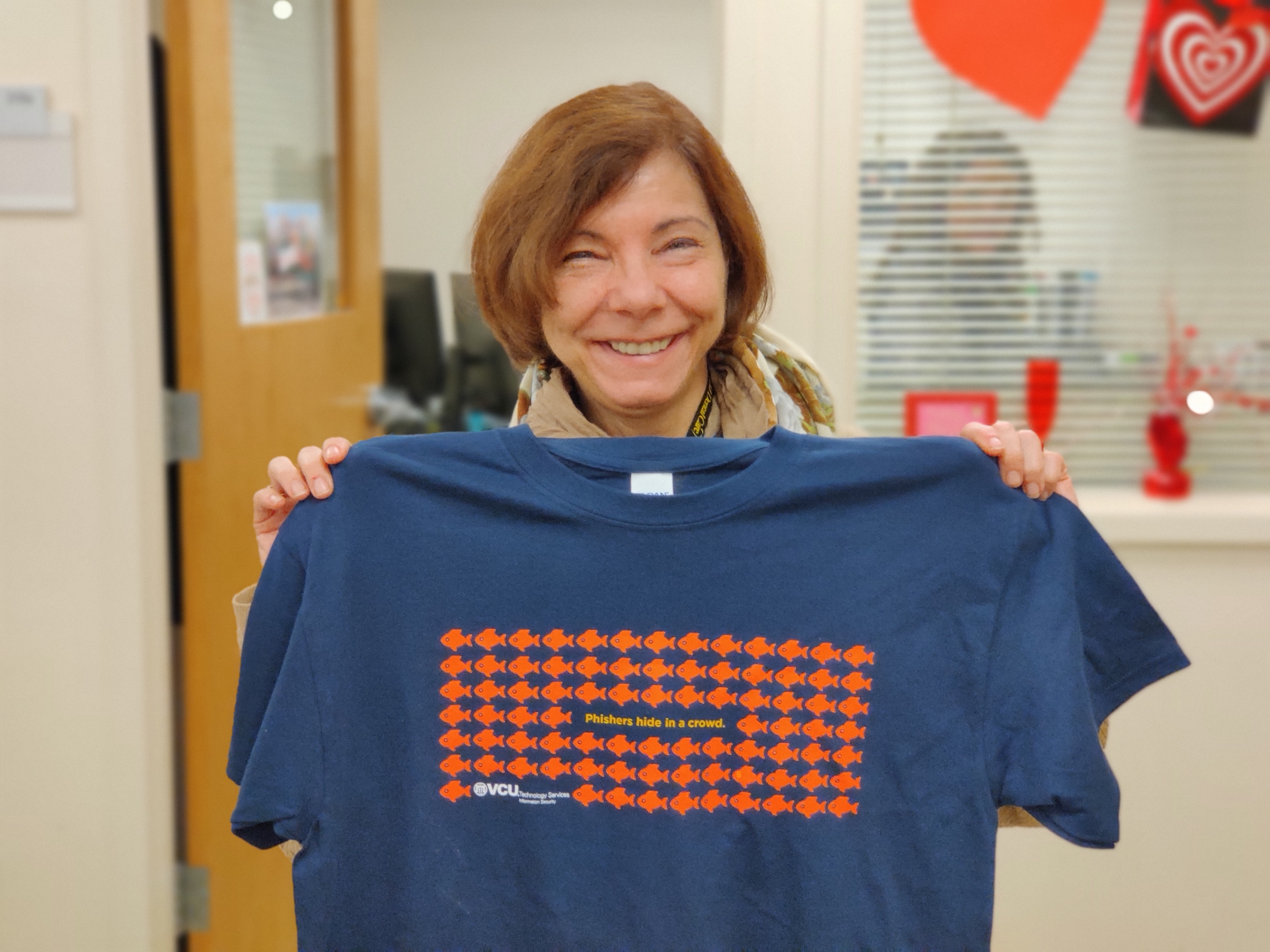 Photo of Louise Wenzell holding a phishers hide in a crowd tee.